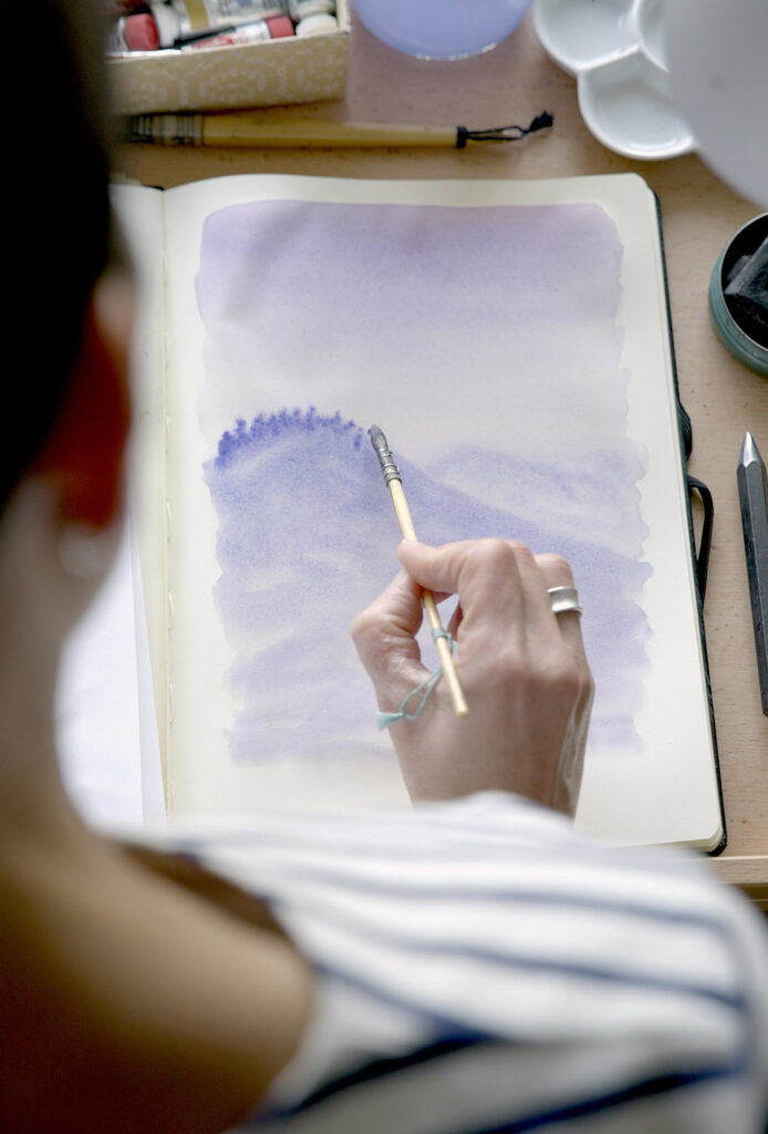 Photograph of Marine placing her brush on a sketchbook.