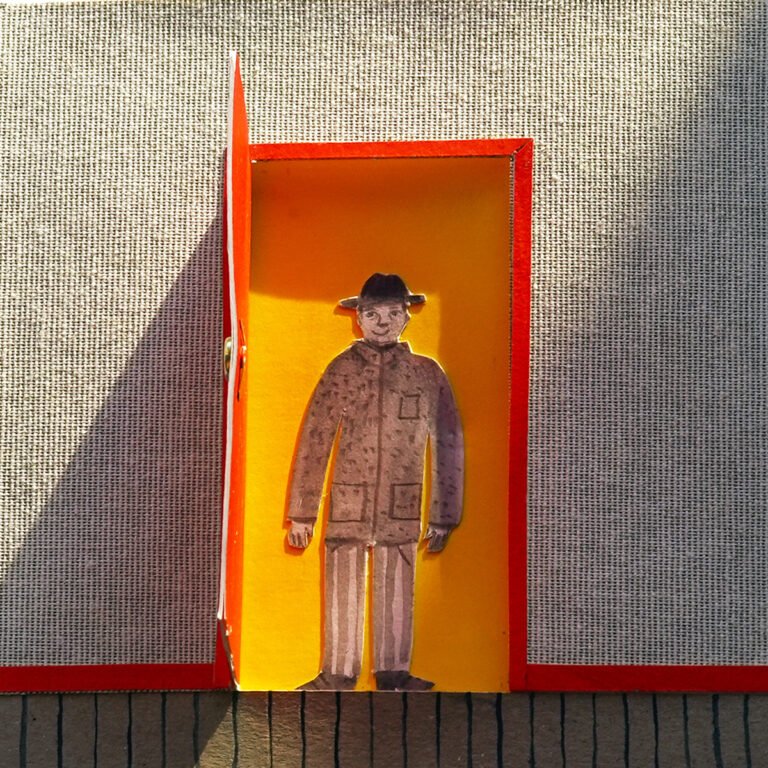 Photographie d'un livre tactile ouvert. Des mains ouvre une porte rouge. Un personnage est debout derrière la porte.